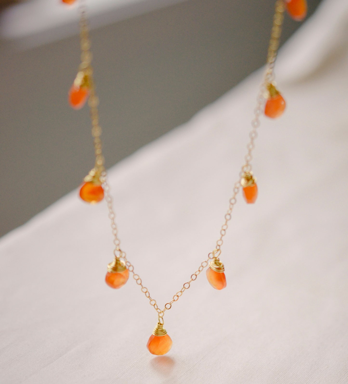 Handmade necklace featuring nine natural Carnelian gemstones set onto a gold filled chain. Sterling Silver is also available.