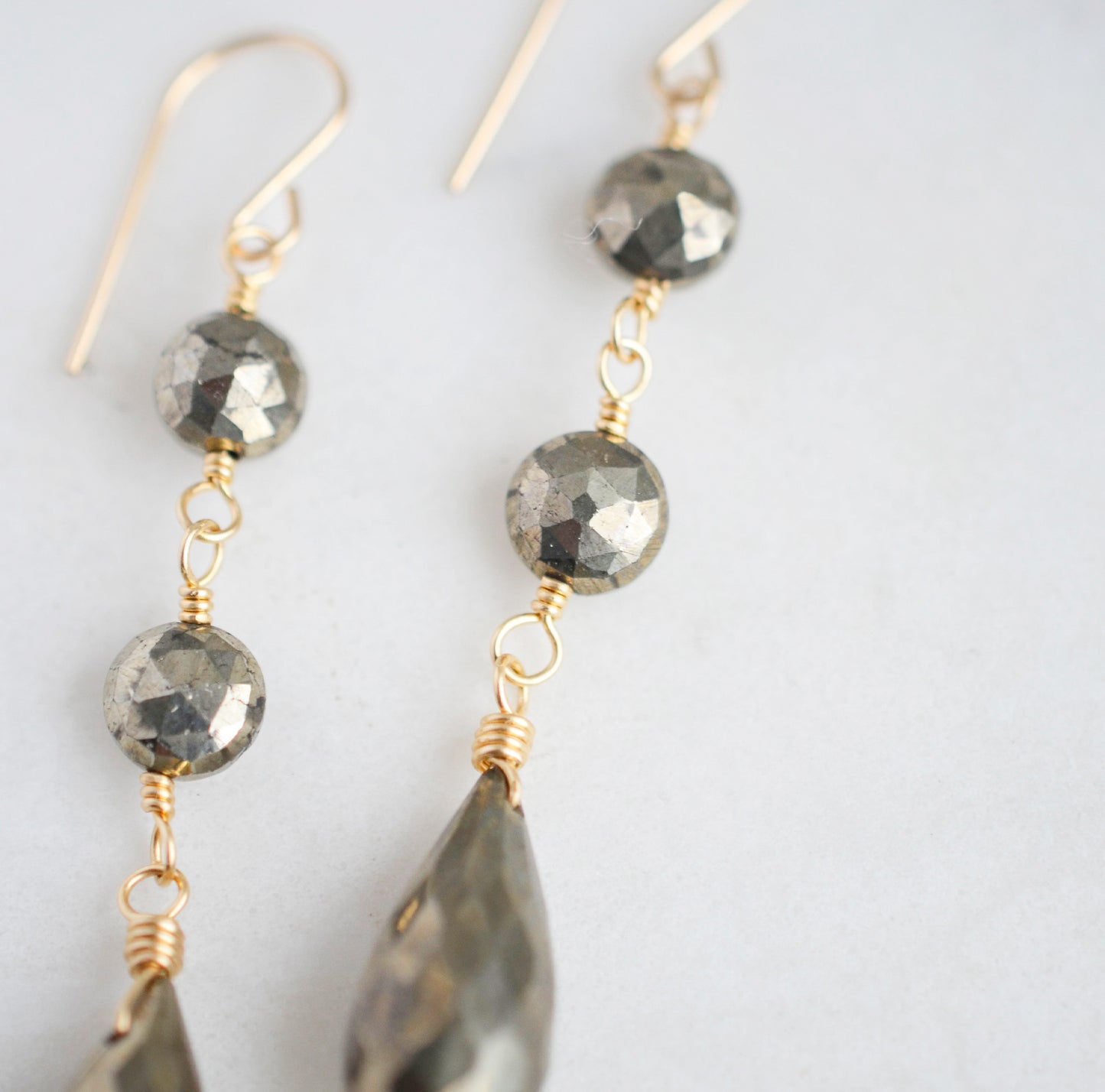 Close up of faceted pyrite crystals in the long dangle earrings.