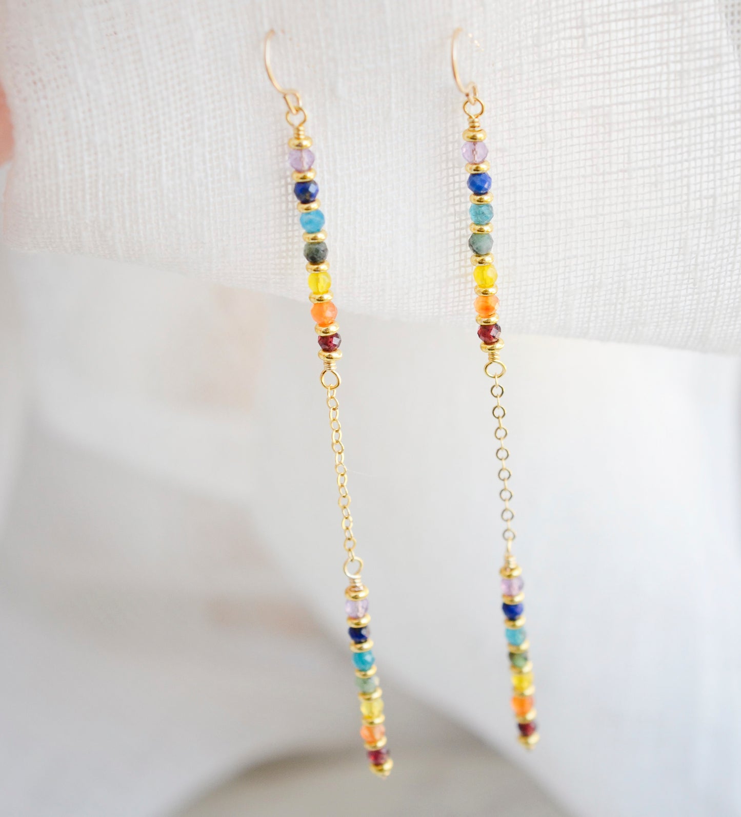 Two long, straight bars of crystals arranged in a rainbow pattern separated by a dainty chain. The gold style is shown.