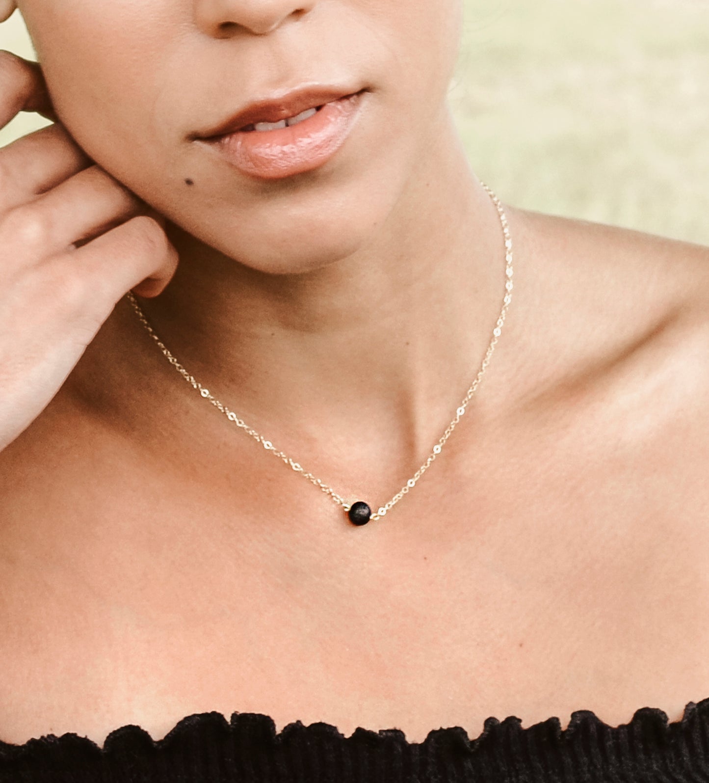 Natural round black Lava, or Basalt, stone placed onto a sterling silver chain. Modeled image.