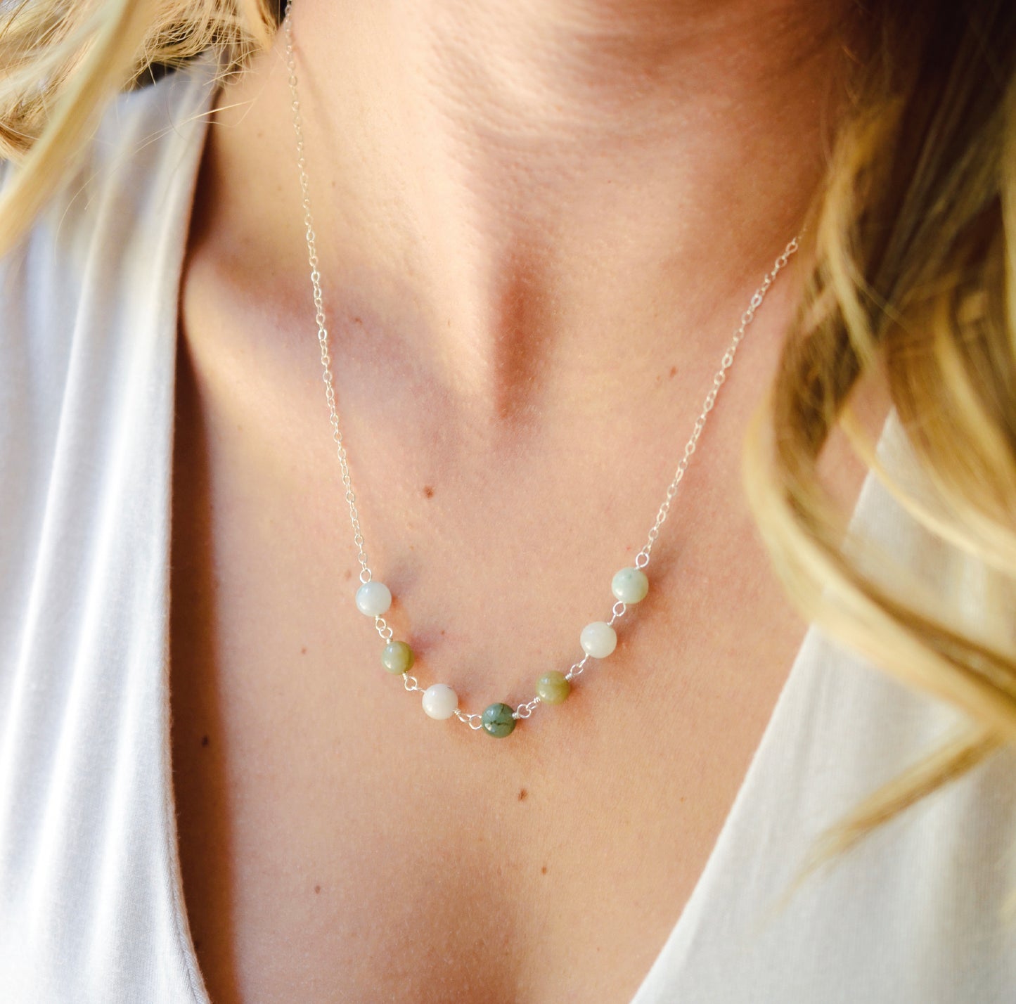 Modeled image of a sterling silver style. A multi-color burma jade necklace featuring seven round green, brown, yellow, or blue natural stones. Handmade in Connecticut by Gemnia Jewelry.