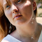 Long clear crystal quartz earrings with two teardrop dangles hanging from a dainty chain. Shown in sterling silver.