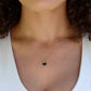 Black Onyx gold heart necklace. A black stone heart bezeled in gold is suspended from a 14k gold filled chain. Modeled image.