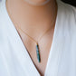 Long green, white, and clear real natural moss agate stone set on a 14k gold filled chain. The pendant is a long thin oval shape. Modeled image.