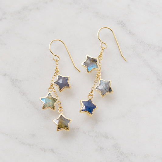 A pair of handmade gold dangle earrings with three star-shaped labradorite stones on each dangle. The metal is 14k gold filled, but they are also available in sterling silver. Handmade celestial jewelry by Gemnia in Connecticut.
