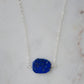 Natural blue lapis lazuli slice set onto a sterling silver chain. The stone is smooth polished with raw edges and oval in shape. Natural pyrite and calcite flecks are visible within each stone. 
