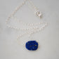 Natural blue lapis lazuli slice set onto a sterling silver chain. The stone is smooth polished with raw edges and oval in shape. Natural pyrite and calcite flecks are visible within each stone. 