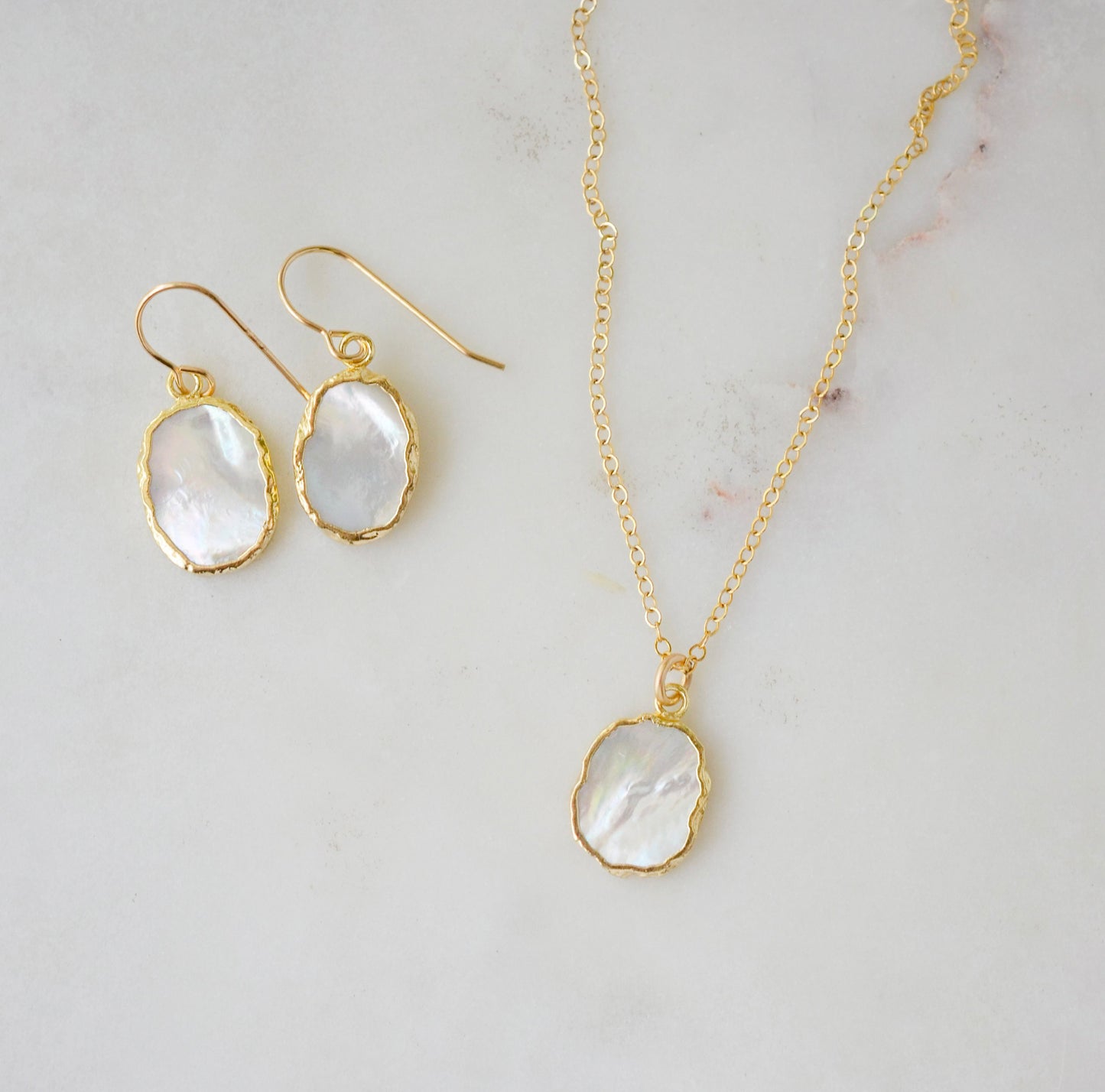 A matching set of mother of pearl earrings and necklace shown in gold. Handmade in Connecticut by Gemnia.