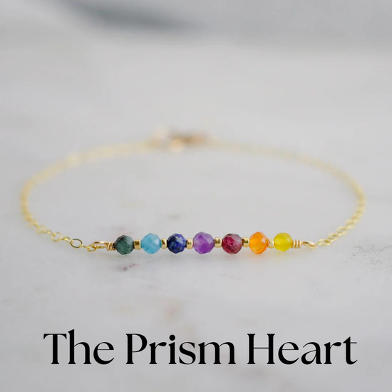 Multicolored beaded bracelet on a marble surface with 'The Prism Heart' branding.