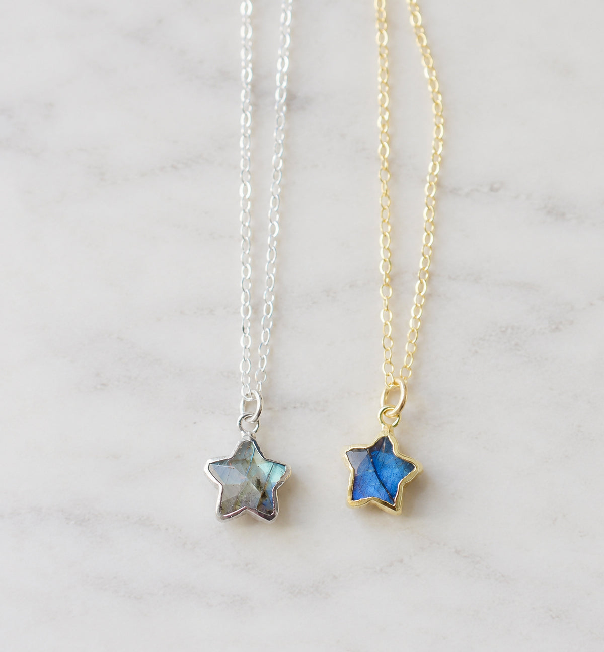 Two star-shaped natural labradorite celestial pendant necklaces on delicate chains, one in sterling silver silver and the other in 14k gold filled. Handmade jewelry in Connecticut by Gemnia.