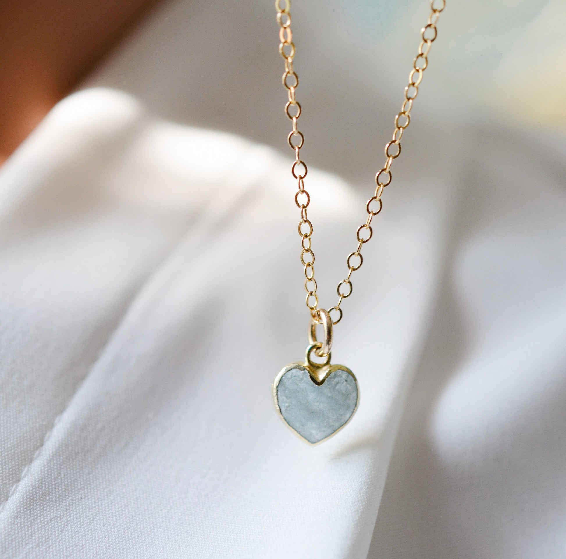 Pale blue natural aquamarine gemstone heart pendant set on a 14k gold filled chain. The stone is genuine and faceted with a 22k gold electroplate bezel.