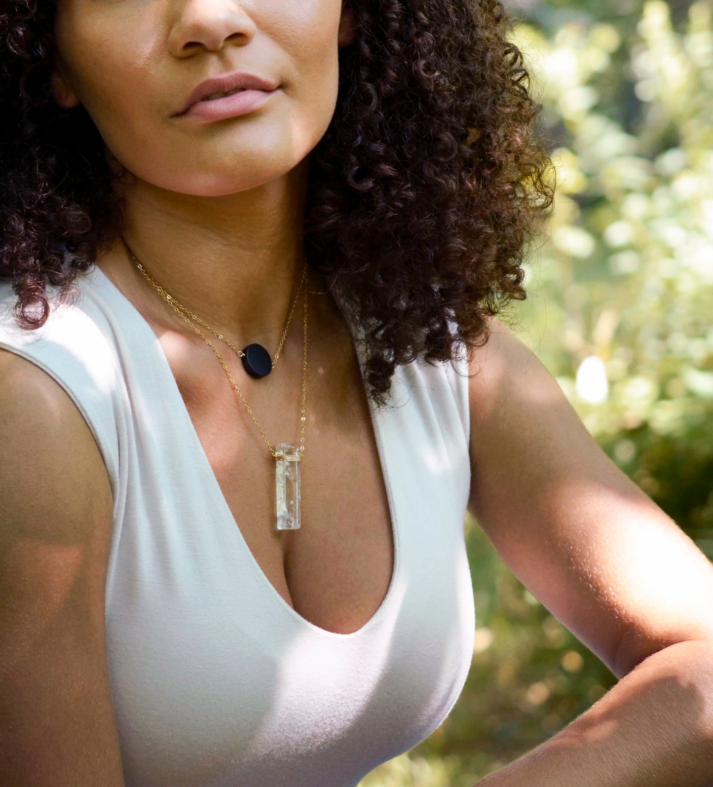 Matte black Onyx circle pendant suspended from a 14k gold filled chain. The stone has a smooth matte finish. Modeled image. Modeled with a crystal Quartz pendant.