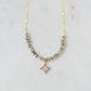 A beaded labradorite gemstone necklace with a white quartz druzy north star pendant at its center. Shown in gold.