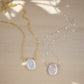 A dainty flat, oval-shaped white freshwater pearl is set within a 14k gold filled or sterling silver chain. Both styles are shown.