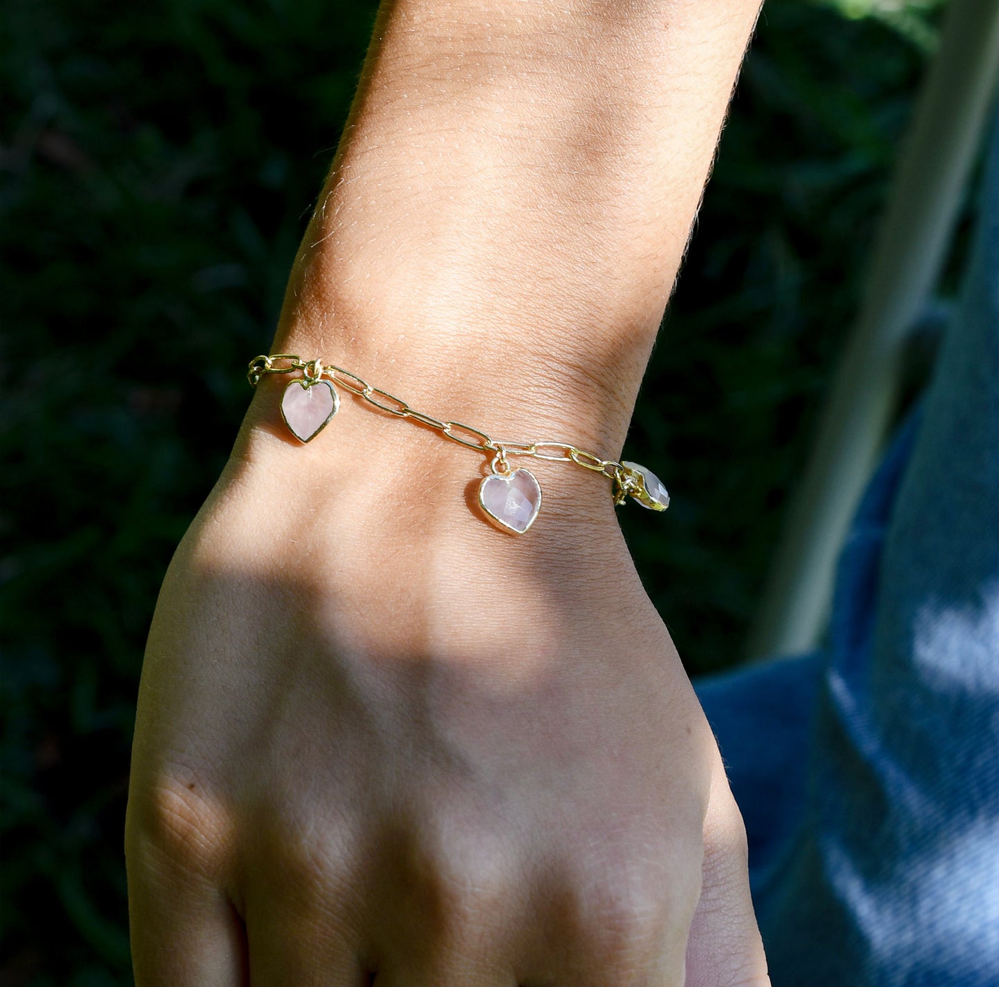 Gold bracelet with heart-shaped charms modeled on a wrist.