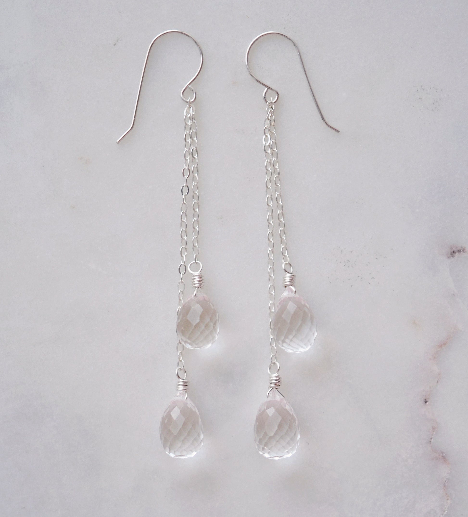 Long clear crystal quartz earrings with two teardrop dangles hanging from a dainty sterling silver chain.