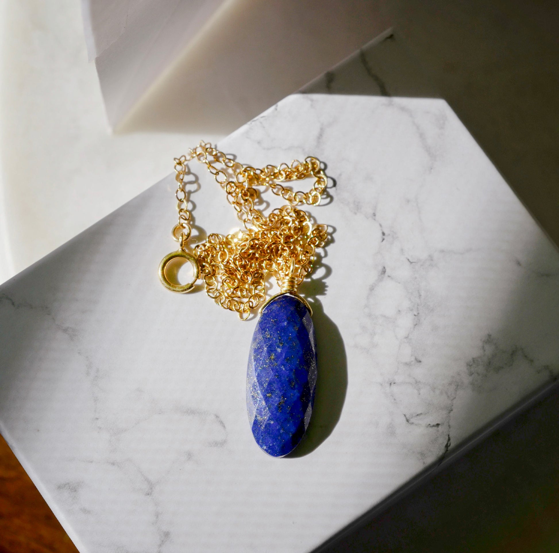 A handcrafted genuine blue lapis lazuli crystal pendant on a dainty 14k gold filled chain. This necklace is handmade in the USA by Gemnia Jewelry.
