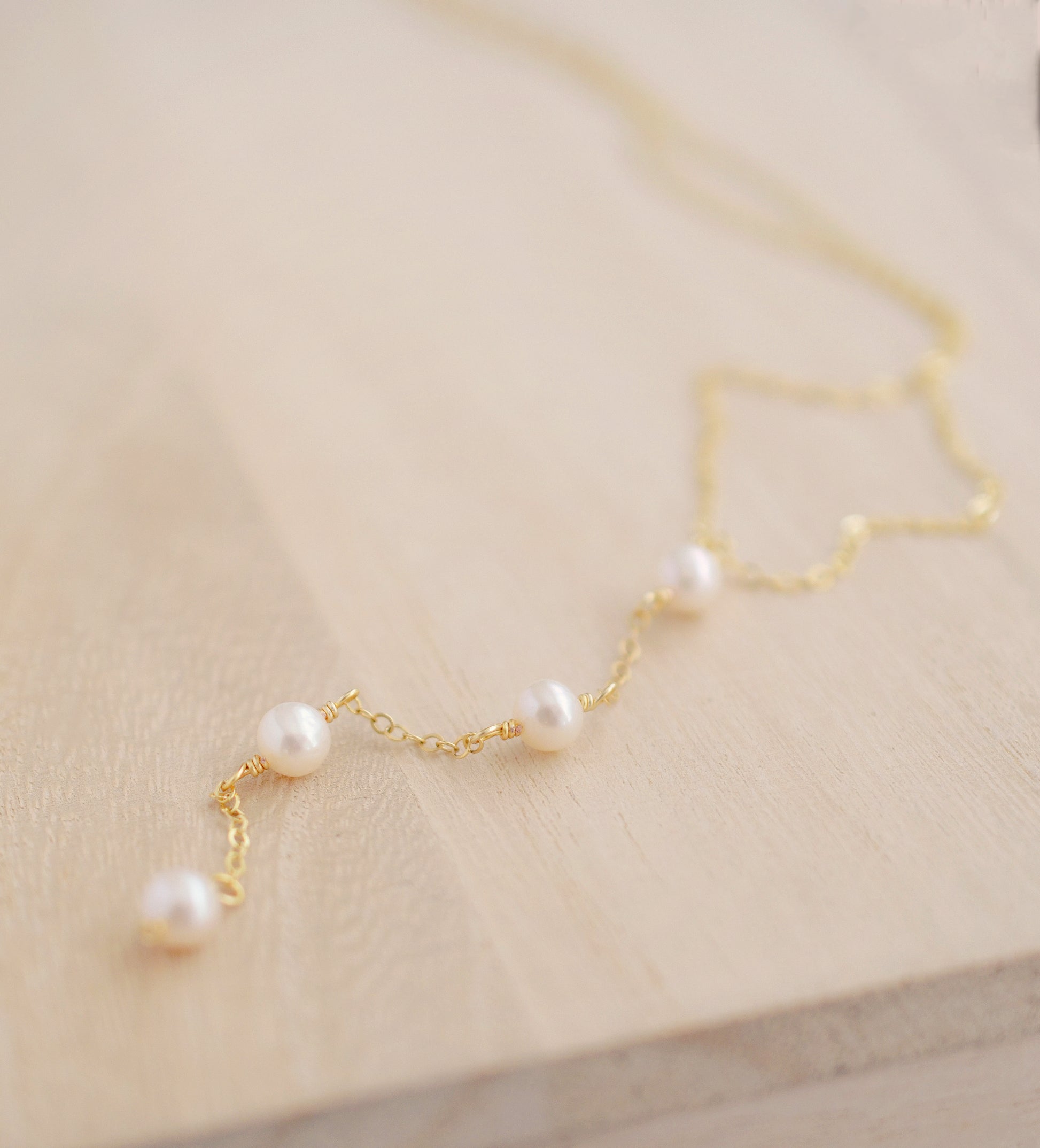 Four semi-round white freshwater pearls are suspended in a Y-style necklace on a 14k gold filled chain. Each pearl is approximately one inch apart. This necklace is also available in sterling silver.