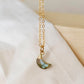 A minimalist, dainty crescent moon pendant handmade from natural labradorite gemstone, set on a 14k gold filled chain. Made in Connecticut by Gemnia.