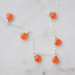 Close up of the genuine orange carnelian crystals set on a sterling silver chain necklace.