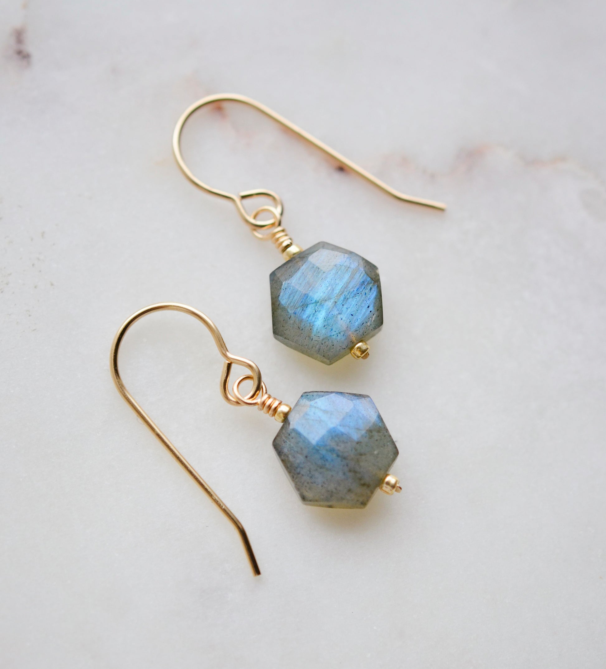 Blue flashing Labradorite gemstones in a faceted hexagonal shape dangle from 14k gold filled earring hooks. Small gold beads accent below the stone. Also available in sterling silver.