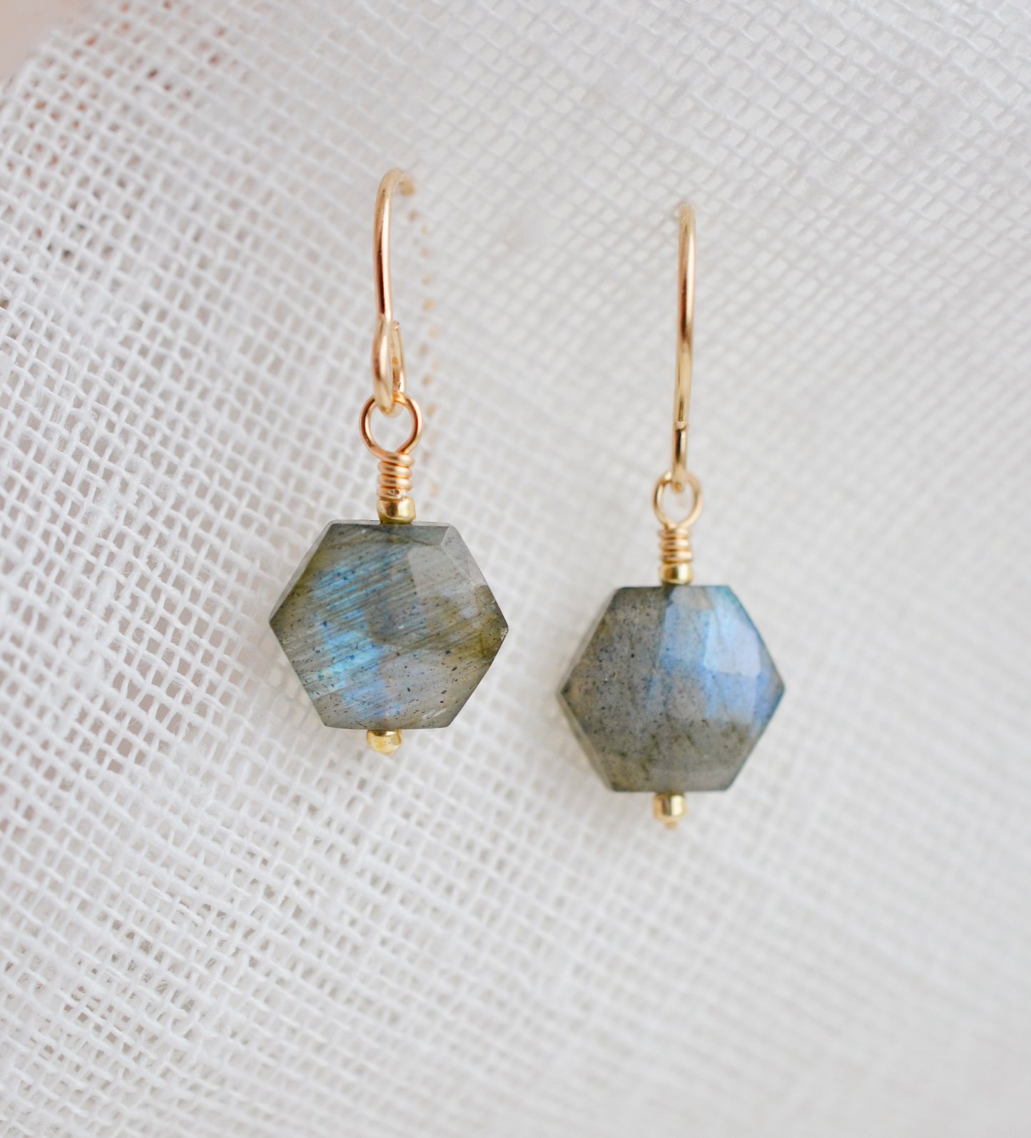 Blue flashing Labradorite gemstones in a faceted hexagonal shape dangle from 14k gold filled earring hooks. Small gold beads accent below the stone. Also available in sterling silver.