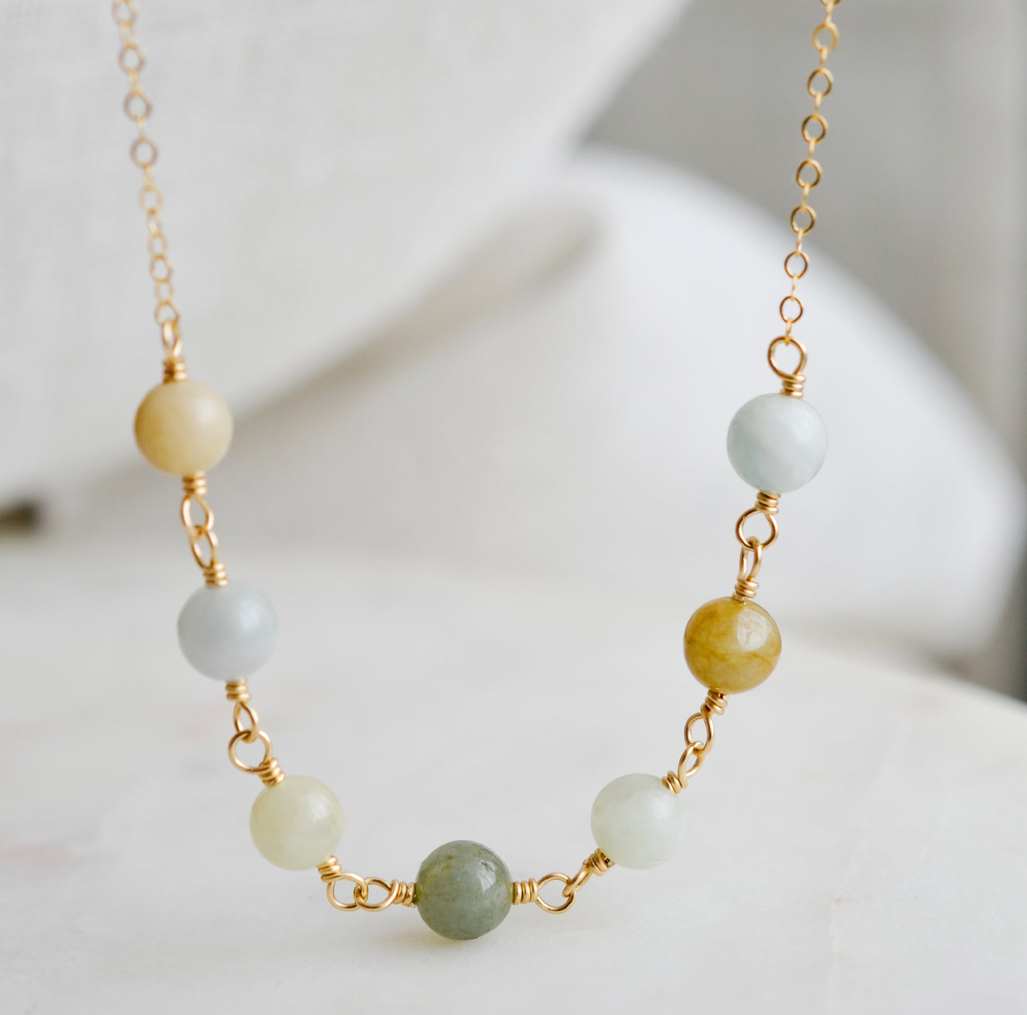A multi-color burma jade necklace featuring seven round green, brown, yellow, or blue natural stones. Handmade in Connecticut by Gemnia Jewelry.