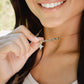 Woman holding a gold necklace with a star pendant. A beaded labradorite gemstone necklace with a white quartz druzy north star pendant at its center. Shown in gold.