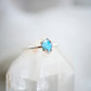 Irregular shaped Labradorite slice gemstone set onto a sterling silver ring band. The stone in the image flashes blue. 