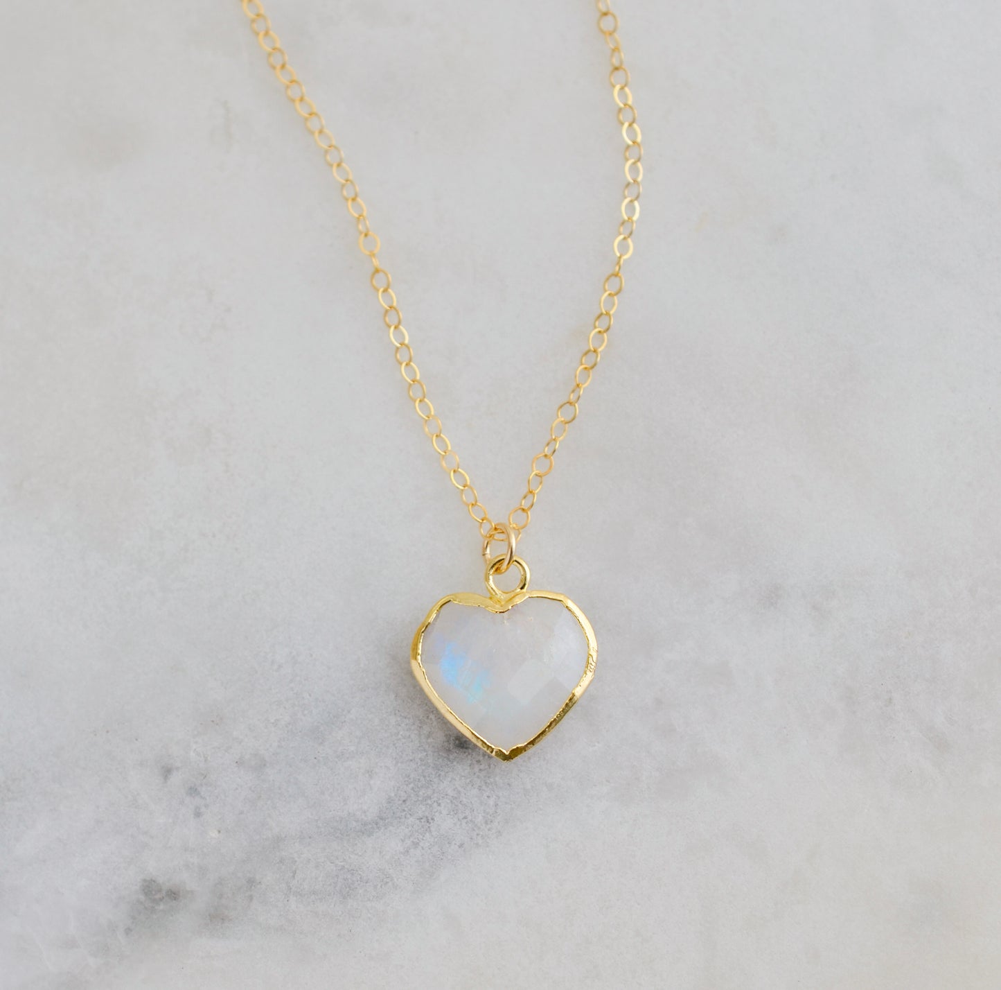 Gold heart-shaped necklace with a natural white rainbow moonstone pendant on a 14k gold filled chain. Handmade in USA artisan jewelry by Gemnia.