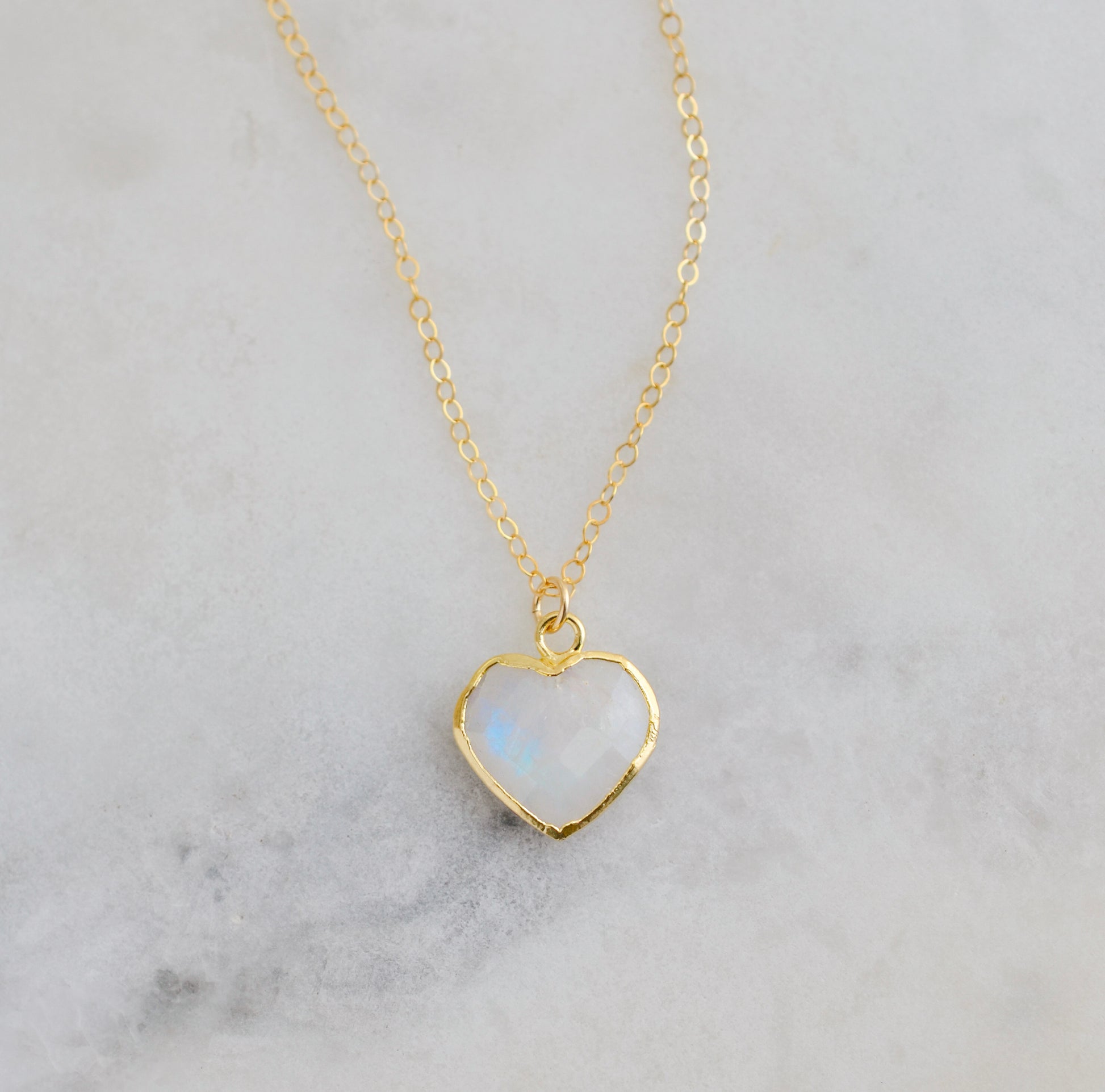 Gold heart-shaped necklace with a natural white rainbow moonstone pendant on a 14k gold filled chain. Handmade in USA artisan jewelry by Gemnia.