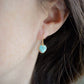 Aqua blue, natural Larimar stone heart earrings in gold. The stones range in blue, white, or green with the occasion mark of brown or black. Modeled image.