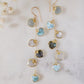 These handmade earrings feature blue and white natural stone hearts bezeled in gold. Each gemstone is a different color and includes: labradorite, larimar, mother of pearl, aquamarine, and rainbow moonstone. Long and light weight they make the perfect romantic gift. They are 3 inches long.
