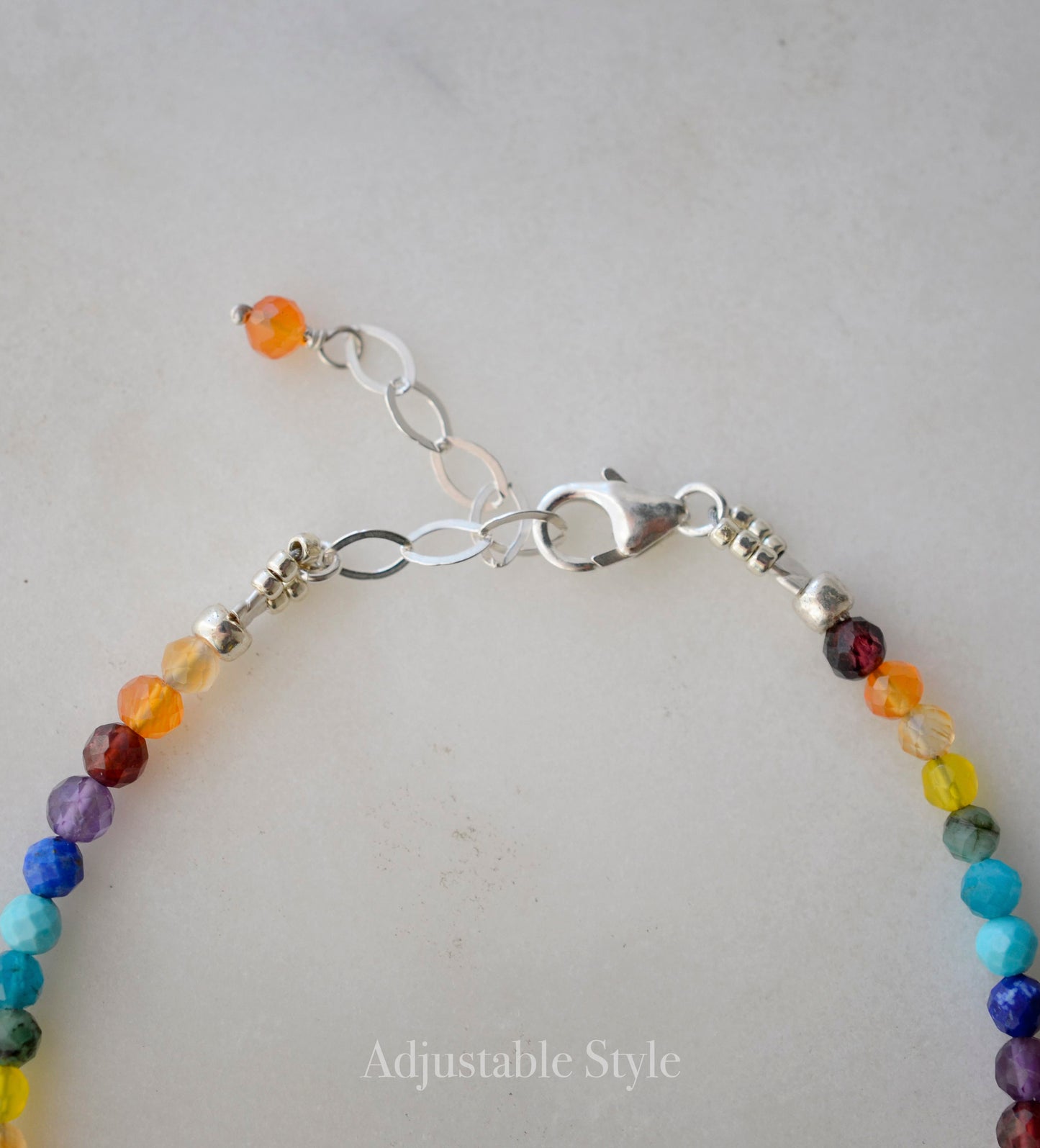 Close up image of the adjustable style in sterling silver. 
Tiny gemstone beaded bracelet in rainbow colors. Colors include: blue, green, yellow, red, orange, and purple.