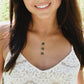 Woman wearing a gold necklace with three genuine blue flash labradorite stones on a dainty 14k gold filled chain.