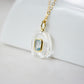 Side view. Handmade Maris necklace featuring a Blue Topaz set inside a clear Rock Crystal frame on a 14K Gold Filled chain. Ideal gift for wife, girlfriend, or mom. Minimalist topaz pendant for layering.
