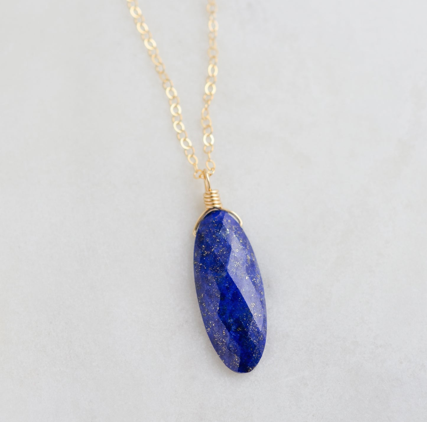 A handmade natural blue lapis lazuli stone pendant on a delicate minimalist 14k gold filled chain. This necklace is made in Connecticut by Gemnia Jewelry.