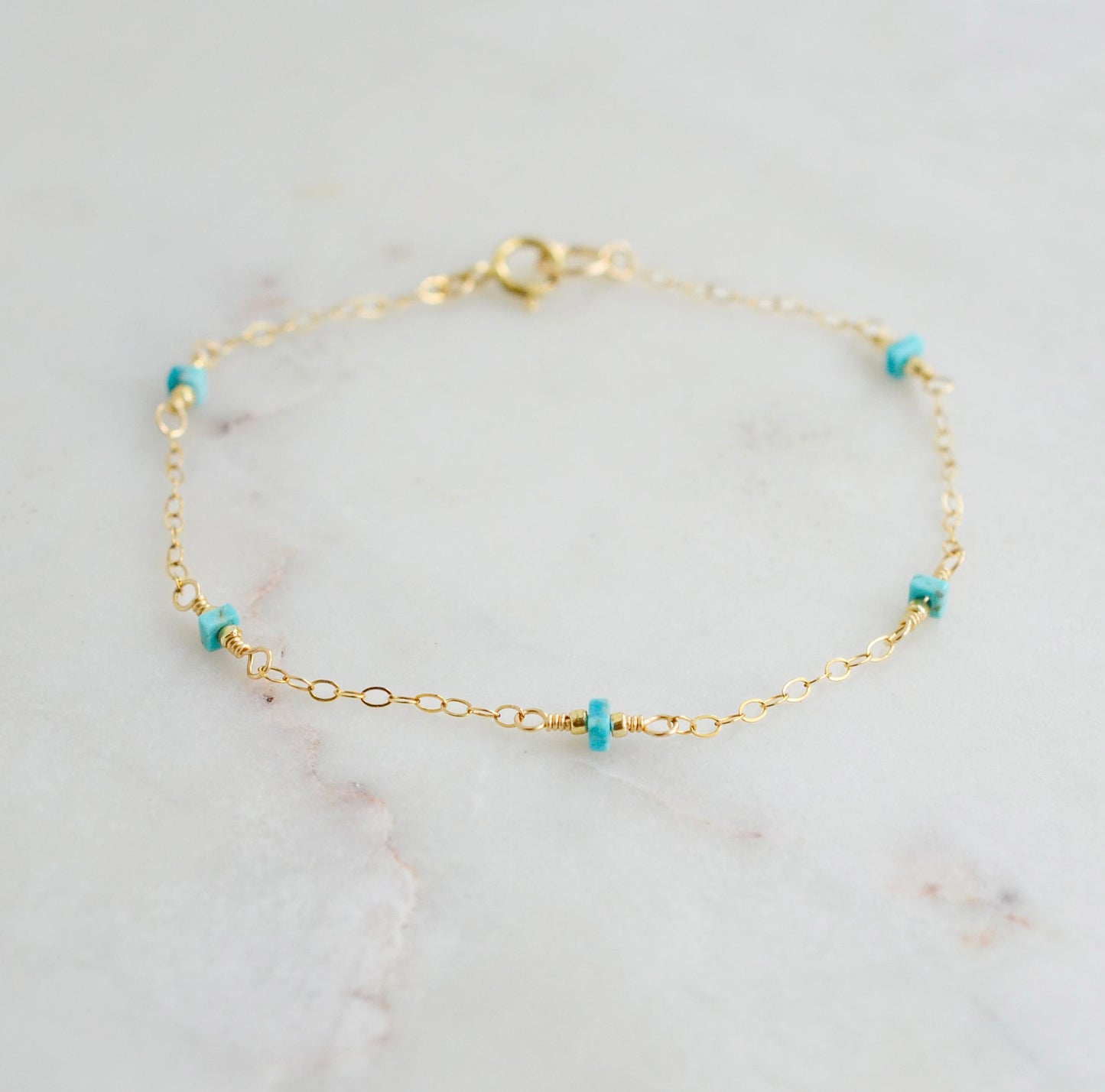 A turquoise and gold filled bracelet with a chain-link design, featuring a gold filled band and turquoise stones. Handmade in Connecticut by Gemnia Jewelry.