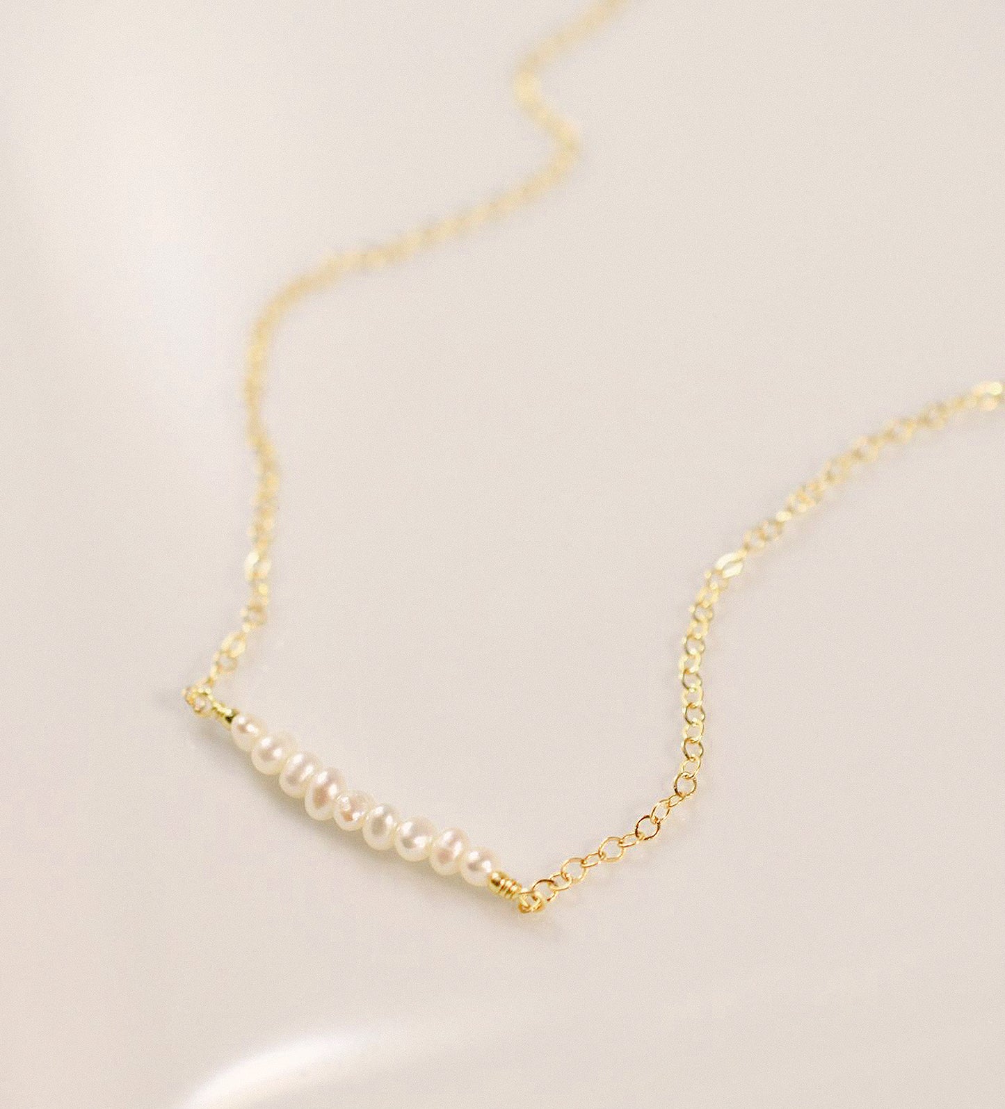 White freshwater pearl bar necklace shown in 14k gold filled. The peals are small and slightly irregular in shape.