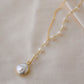 White freshwater pearl necklace with a large coin pearl pendant. Pearls fill one side of the necklace, while the other side is a dainty gold chain.