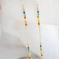 Two long, straight bars of crystals arranged in a rainbow pattern separated by a dainty chain. The gold style is shown. 