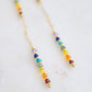 Close up. Two long, straight bars of crystals arranged in a rainbow pattern separated by a dainty chain. The gold style is shown. 
