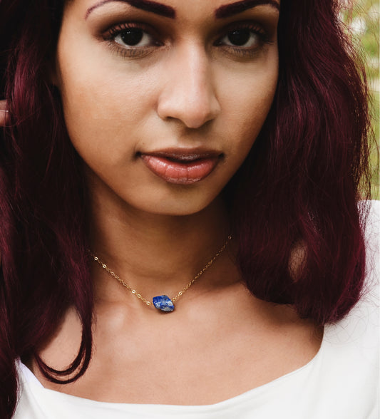 Raw blue lapis lazuli stone suspended from a gold chain. Modeled Image. 