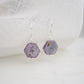 Purple-pink raw ruby stones suspended from sterling silver earwires. The stones are rough and in their natural hexagonal shape. 