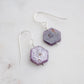 Purple-pink raw ruby stones suspended from sterling silver earwires. The stones are rough and in their natural hexagonal shape. 
