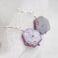 Purple-pink raw ruby stones suspended from sterling silver earwires. The stones are rough and in their natural hexagonal shape. 