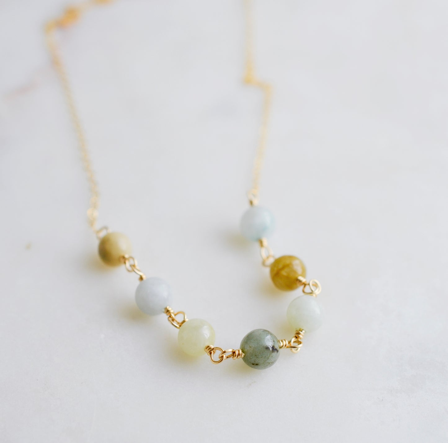 A multi-color burma jade necklace featuring seven round green, brown, yellow, or blue natural stones. Handmade in Connecticut by Gemnia Jewelry.