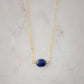 Small blue sapphire stone set onto a gold chain. The stone is a puffed oval shape. 