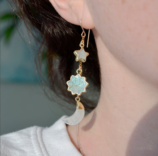 Modeled image of a sun, moon, and star celestial dangle earrings. 