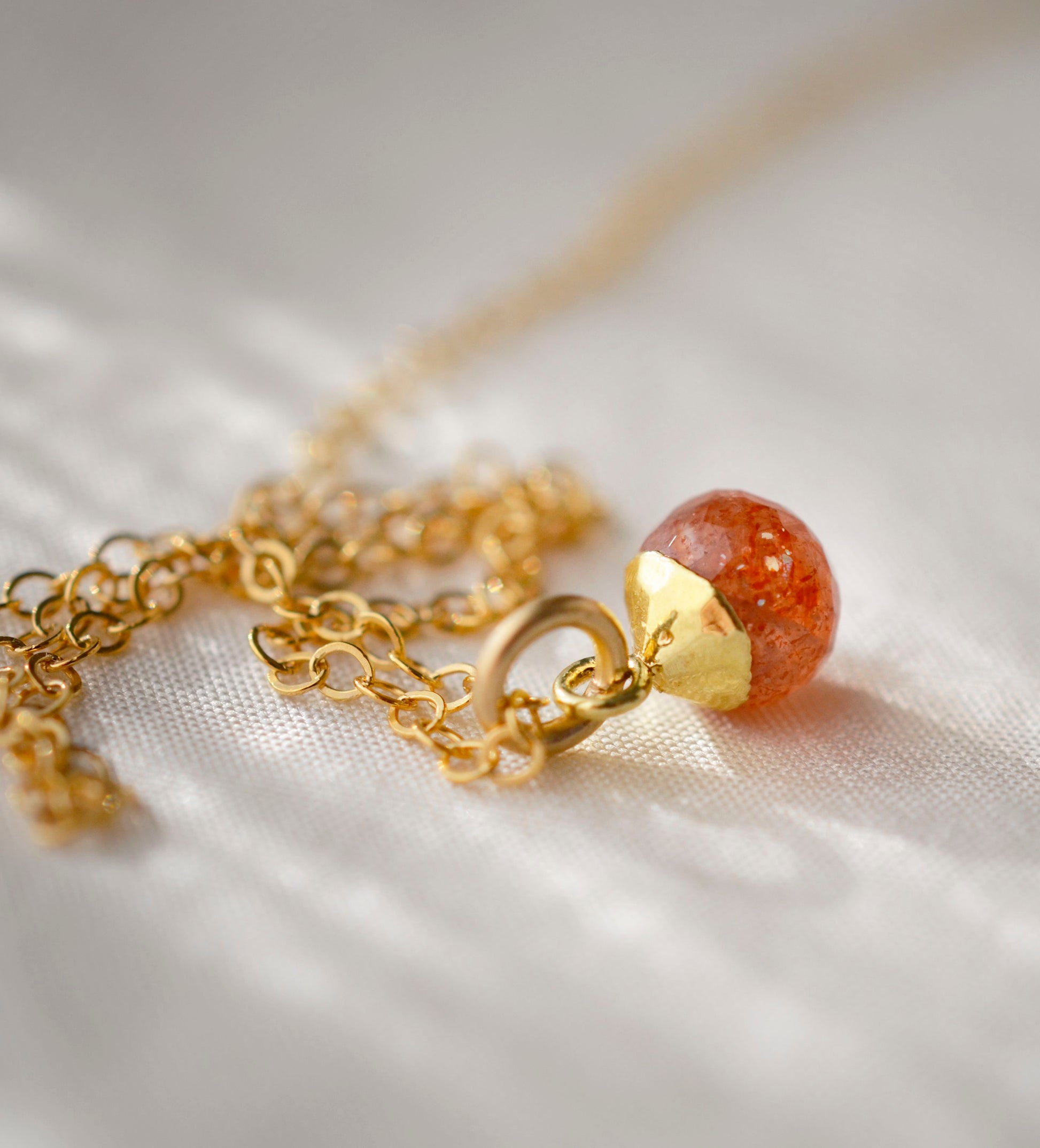 Natural orange Sunstone necklace. The stone is a faceted round and set onto a 14k gold filled chain.